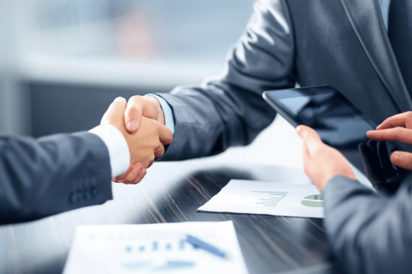 Two professionals shaking hands over a desk, signifying an agreement or approval from a payday loan platform.